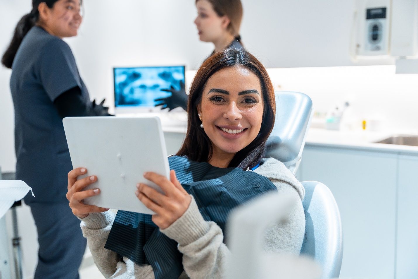 Patient smiling while holding mirror in treatment chair