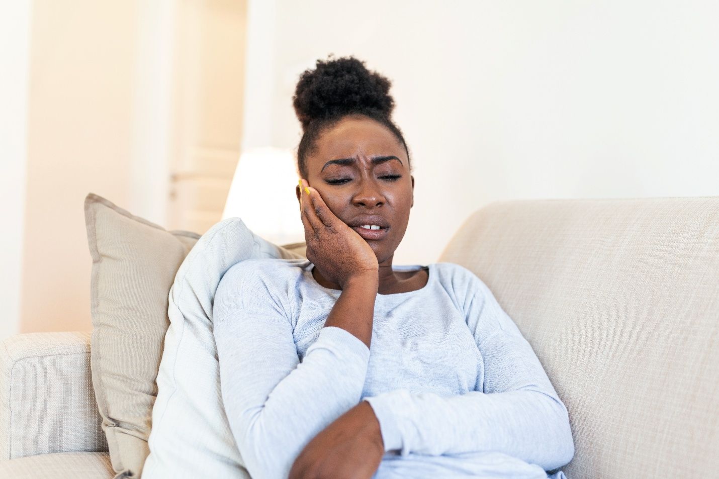 Woman with toothache sitting on couch at home