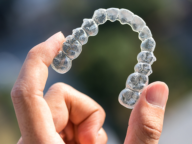 Patient holding clear aligners — discreet teeth straightening option