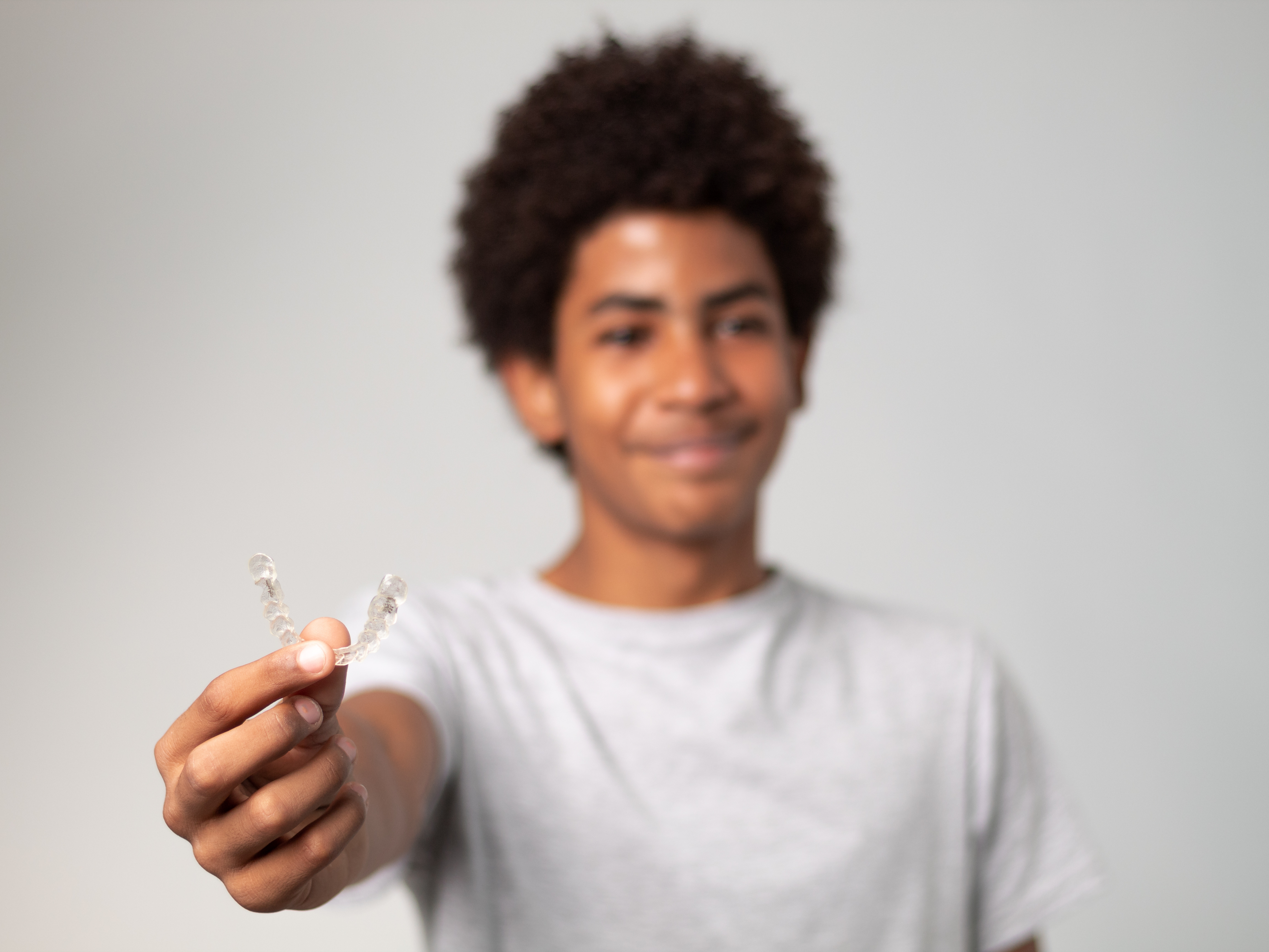 Patient in Alpharetta smiling and holding some Invisalign trays 