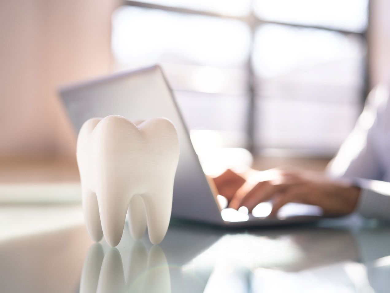 A tooth mold and a person on a laptop in the background