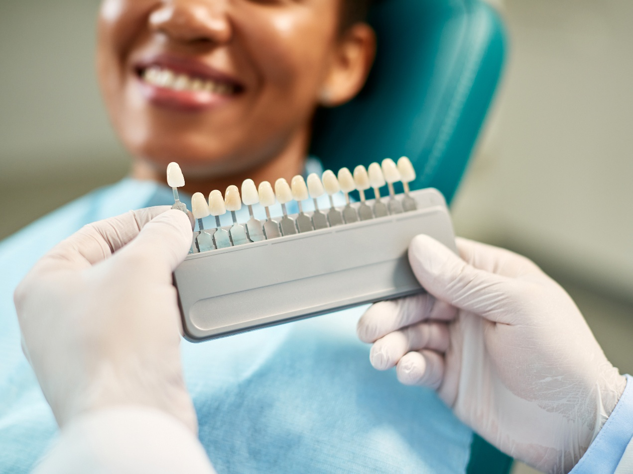 Dentist helping smiling patient select shade of veneer